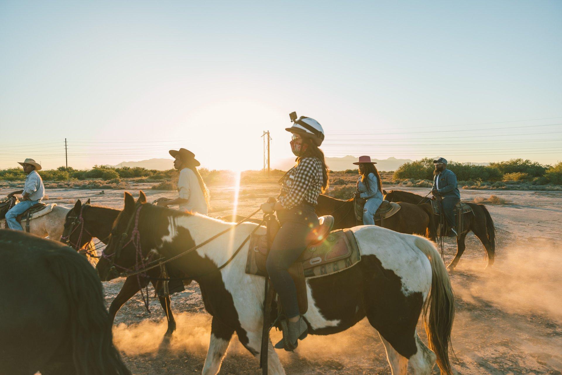 A woman riding a horse with a group of people on a horse behind her